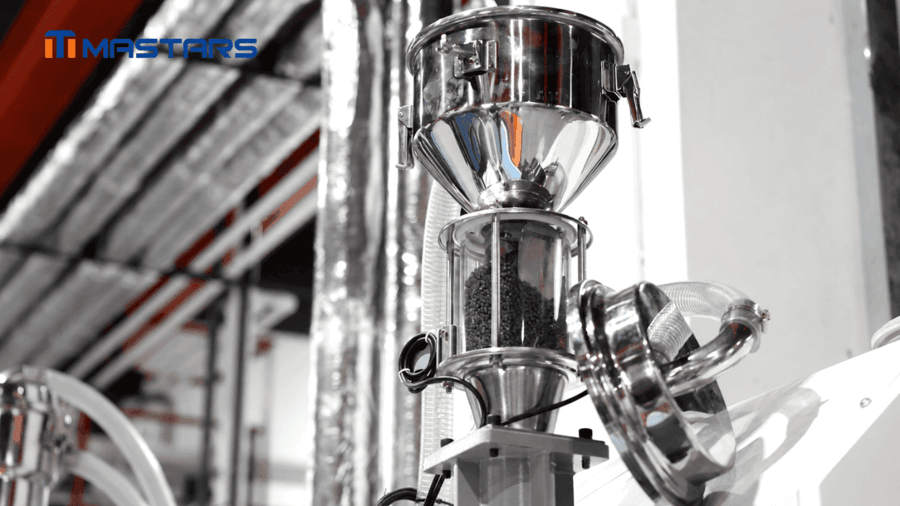 Black engineering plastic pellets in Mastars' injection molding material feeding system.